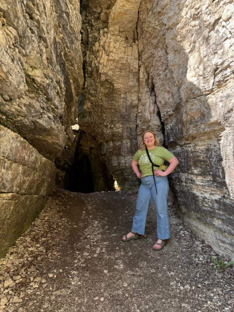 A woman stands at the entrance of Ice Cave State Preserve